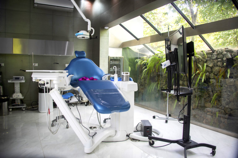 Silla de consultorio dental en consultorio con pared de cristal y plantas